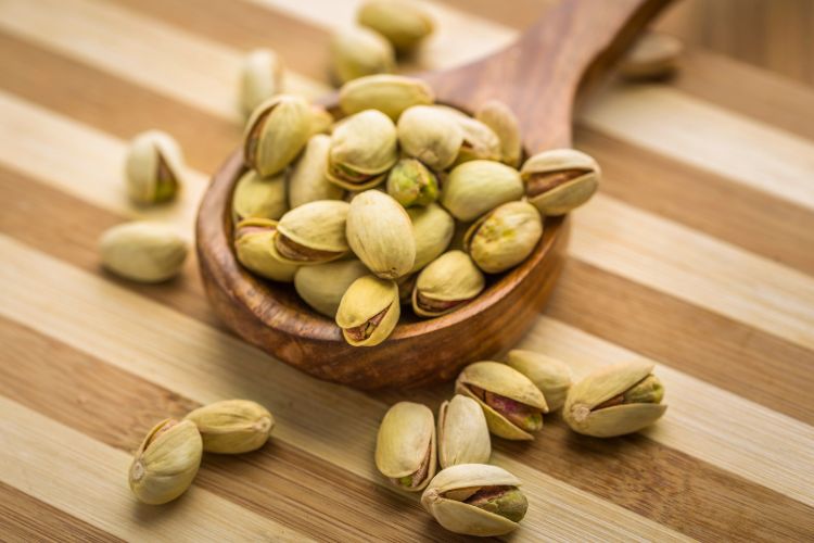 Tudo-Sobre-Pistache Colher de madeira com a noz pistáchio em superfície de madeira