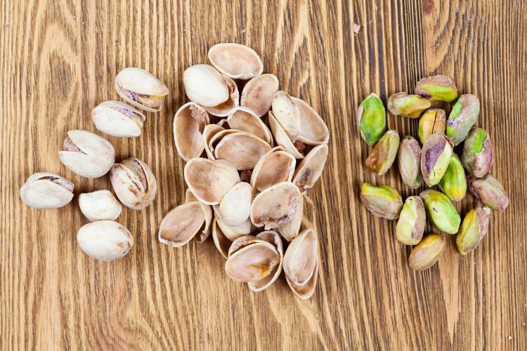 Pistache-Tudo-Sobre-Noz-1 3 versões da noz: noz inteira, só a casca e descascado, em superfície de madeira