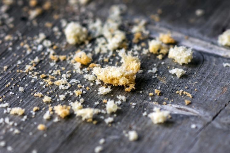 Breadcrumbing-1 Migalhas de pão sobre superfície de madeira escura