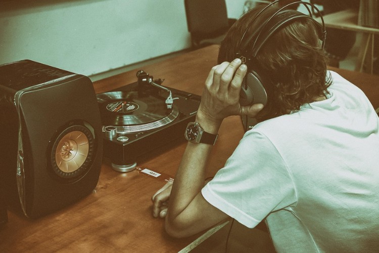 Elitismo-Cultural-1 Homem de pele clara usando blusa branca, ouvindo música em disco de vinil