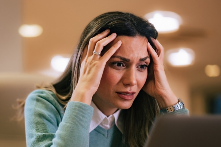Frustacao-Psicanalise-Como-Lidar Mulher com expressão de frustração, mãos na cabeça, olhando para um laptop. A imagem reflete emoções intensas, ideal para ilustrar temas como choque cultural e psicanálise.