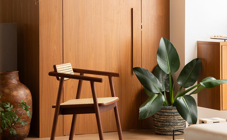 pacová em cesto ao lado de cadeira de madeira em sala minimalista com paleta quente.