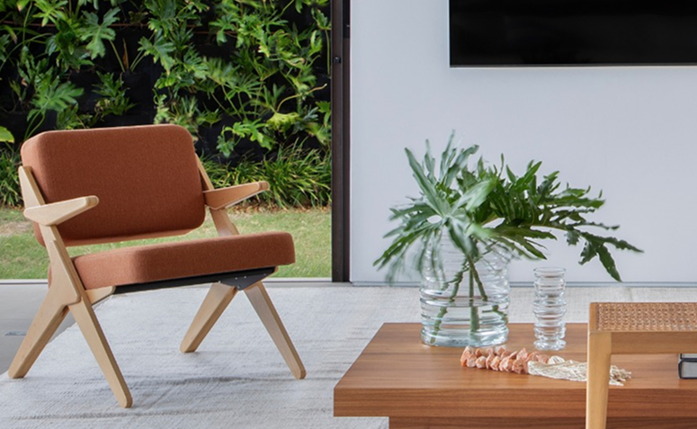 folhas de guaimbê em vaso de vidro sobre mesa de madeira em sala minimalista