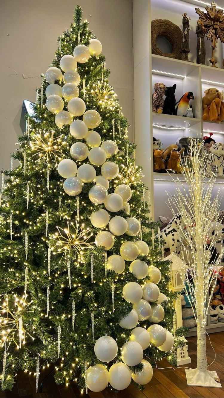 Arvore-De-Natal-Diferente Foto de árvore de Natal verde com pisca-pisca diferente e bolas brancas dispostas em formato de festão