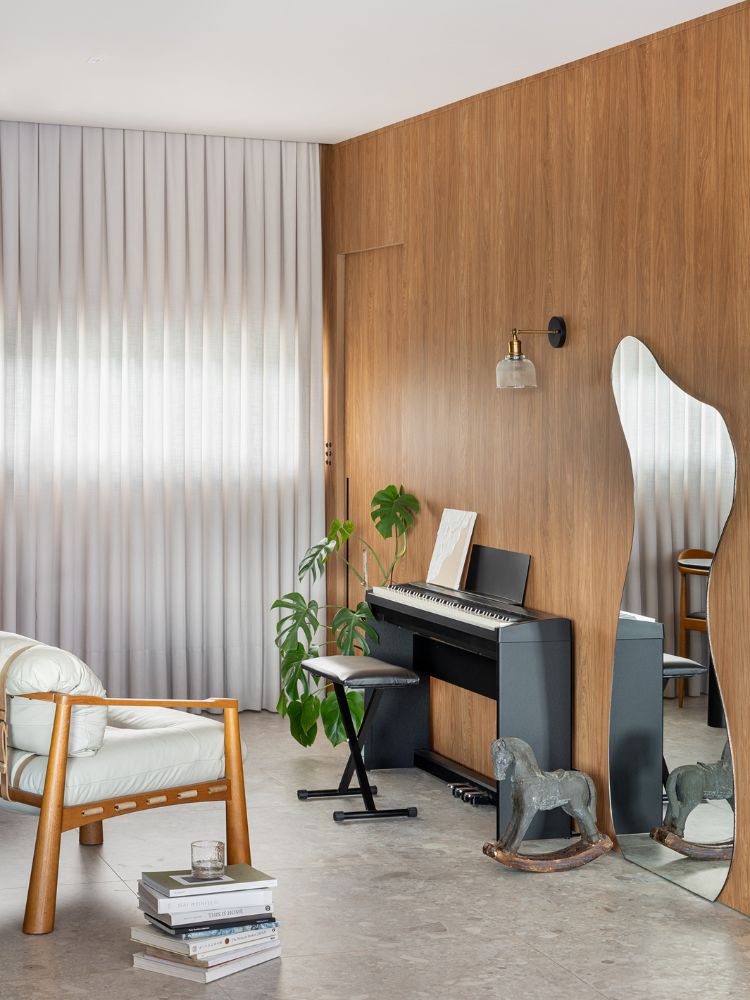 Apartamento-Decorado-De-170M2-16 Zoom em parede de madeira com piano elétrico, espelho orgânico e poltrona