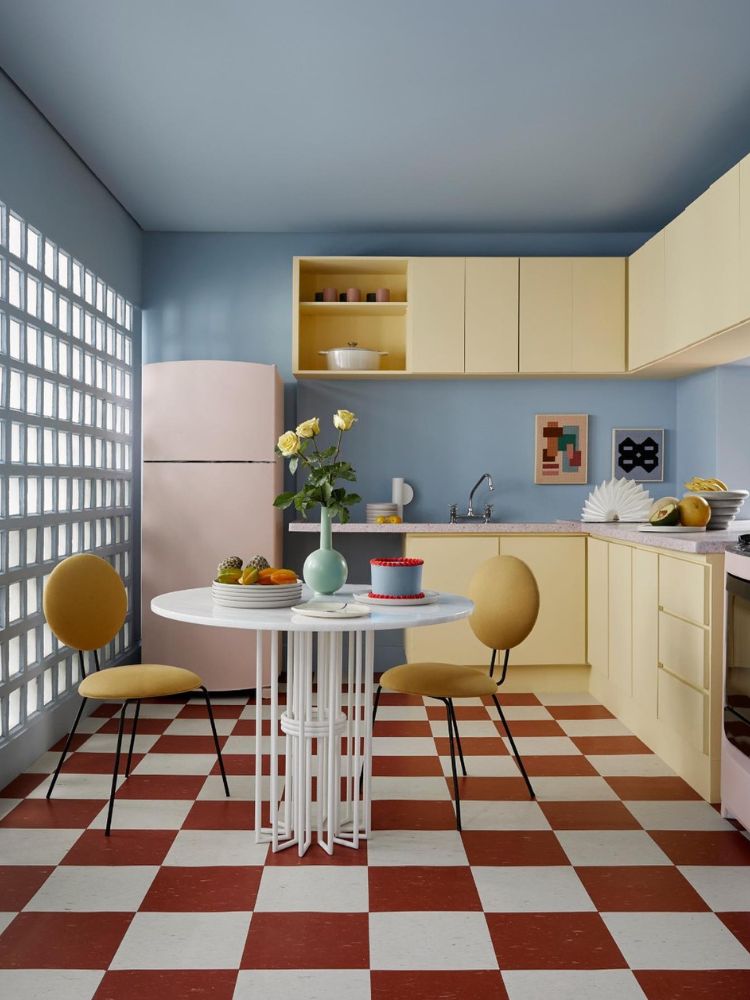 Cozinha-Colorida-13 Cozinha colorida retrô em tons pastéis, com parede azul, móveis amarelo-manteiga, chão quadriculado e terracota e geladeira rosa