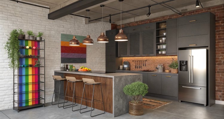 Decoracao-Casa-Lgbtqia-4 Cozinha moderna estilo industrial com armários cinza escuro, parede de tijolos aparentes e iluminação de pendentes metálicos. Ilha central com acabamento em madeira e concreto, prateleira colorida vibrante, vasos decorativos, eletrodomésticos inox e detalhes em plantas. Ambiente funcional e acolhedor.