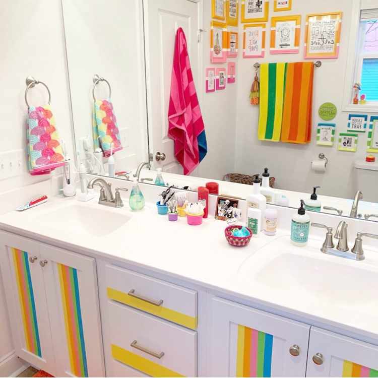 Decorar-Com-As-Cores-Da-Bandeira-Lgbtqia-4 Banheiro com armários brancos com detalhes coloridos, toalhas coloridas e quadros coloridos