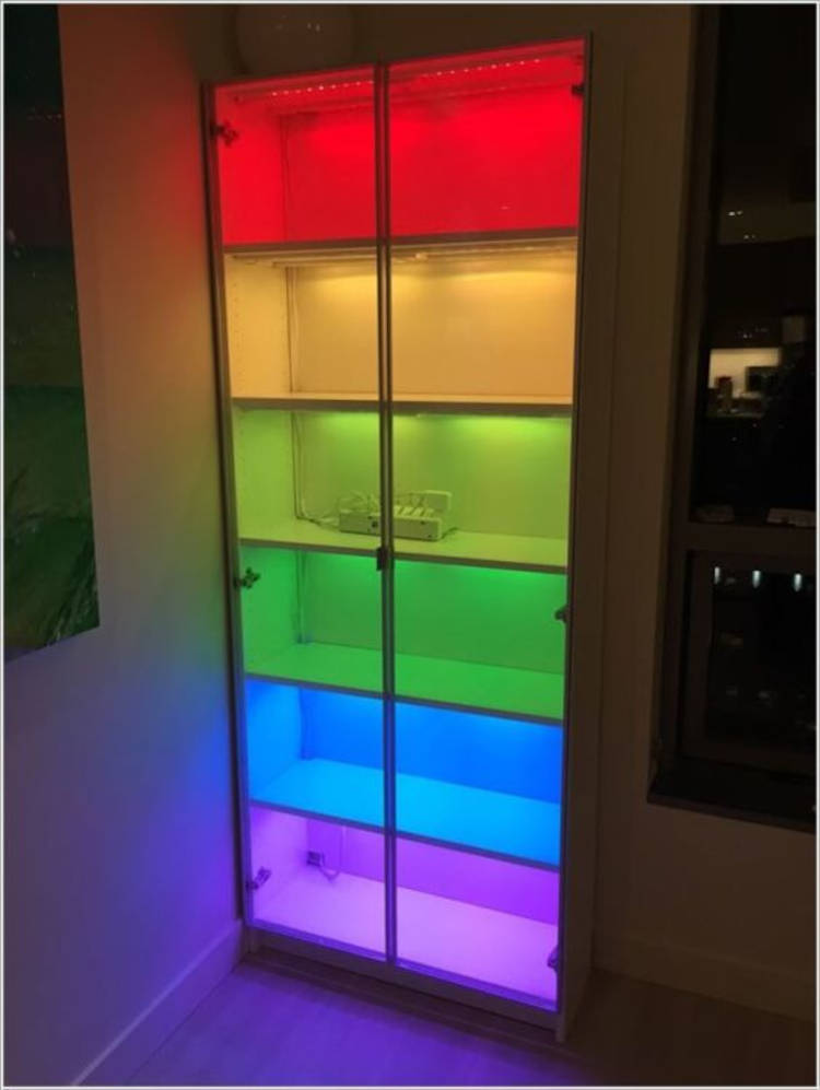 Iluminação Colorida Em Nichos. Estante com 7 andares, cada um iluminado com uma cor do arco-íris