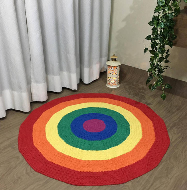 Tapete Da Bandeira Lgbtqia+. Tapete redondo colorido em chão de madeira, ao lado de planta e cortina branca