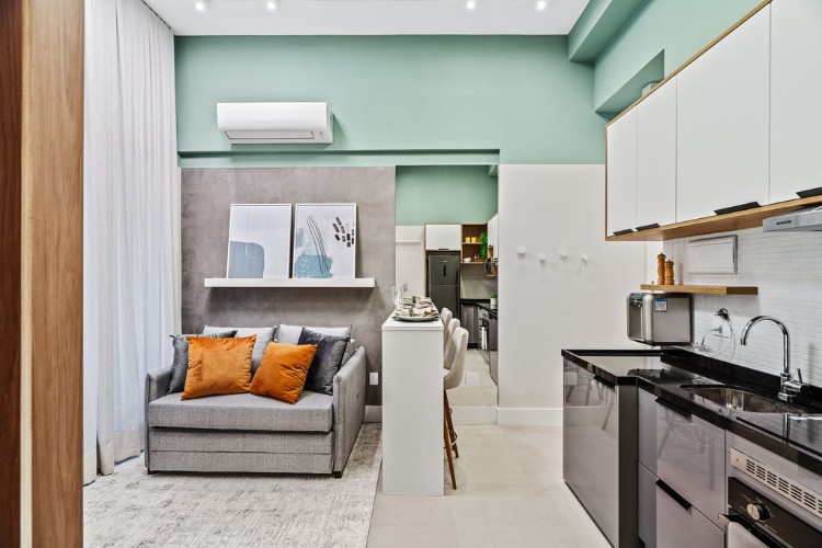 Apartamento-De-37-M2-7 Sala de parede verde com sofá cinza, tapete, integrada com cozinha