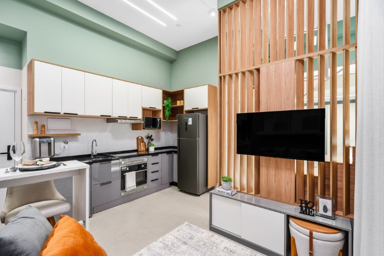 Apartamento-De-37-M2-8 Integração de cozinha em verde, branco e cinza com sala com painel de madeira