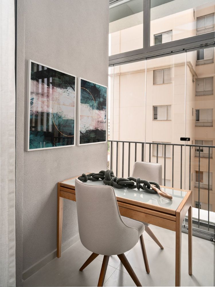 Apartamento-De-37-M2-5 Sacada de parede cinza com quadros, mesa com duas cadeiras e decoração