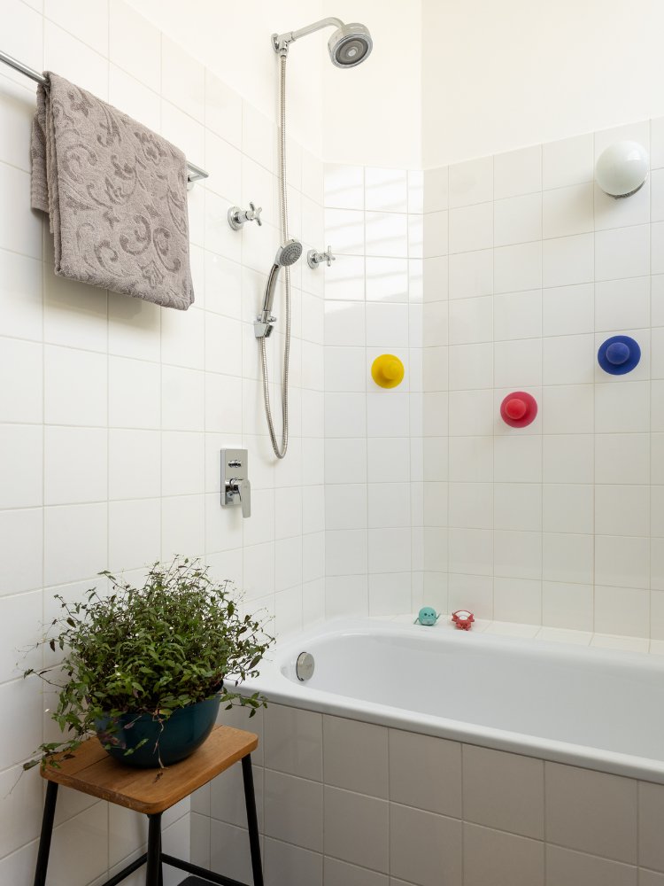 Reforma-Apartamento-100-M2-3 Banheiro branco com banheira e planta, além de brinquedos para criança