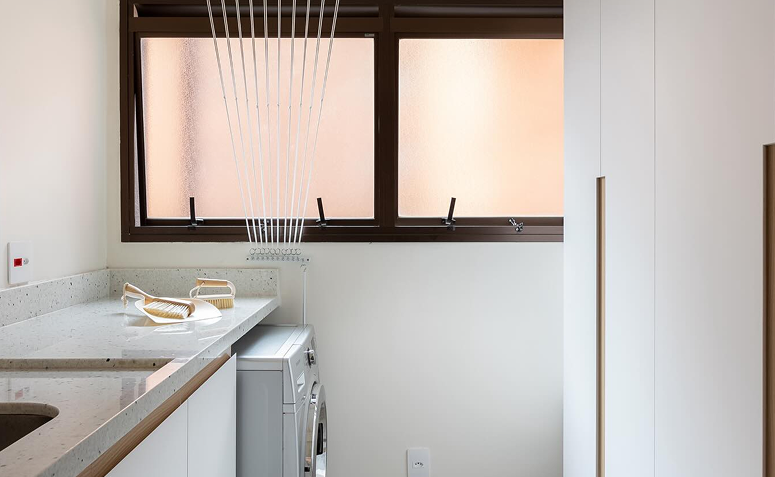 lavanderia organizada com máquina de lavar, bancada e varal de teto