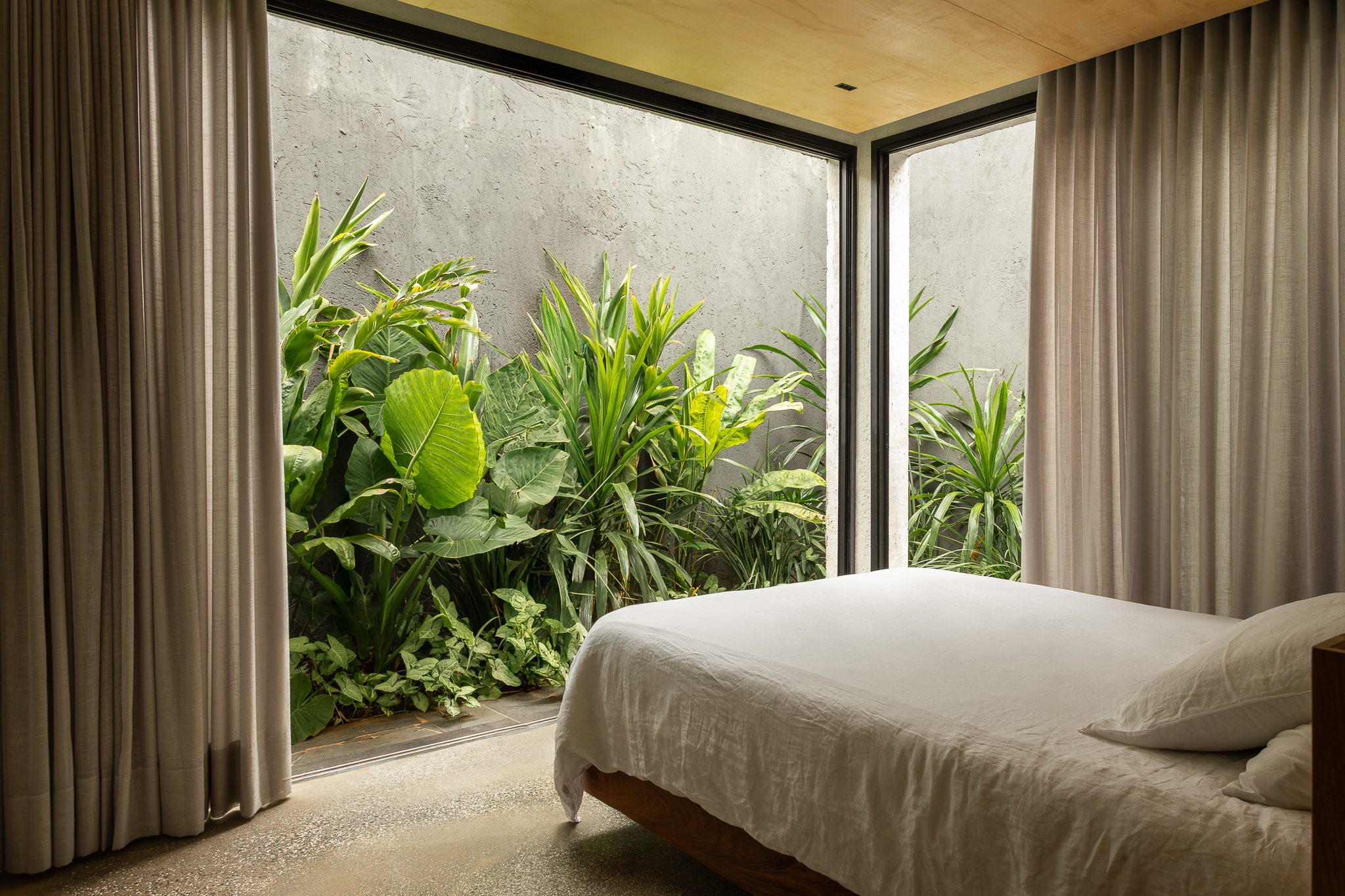 Quarto da Casa Jasmim com decoração minimalista e vista para jardim estreito