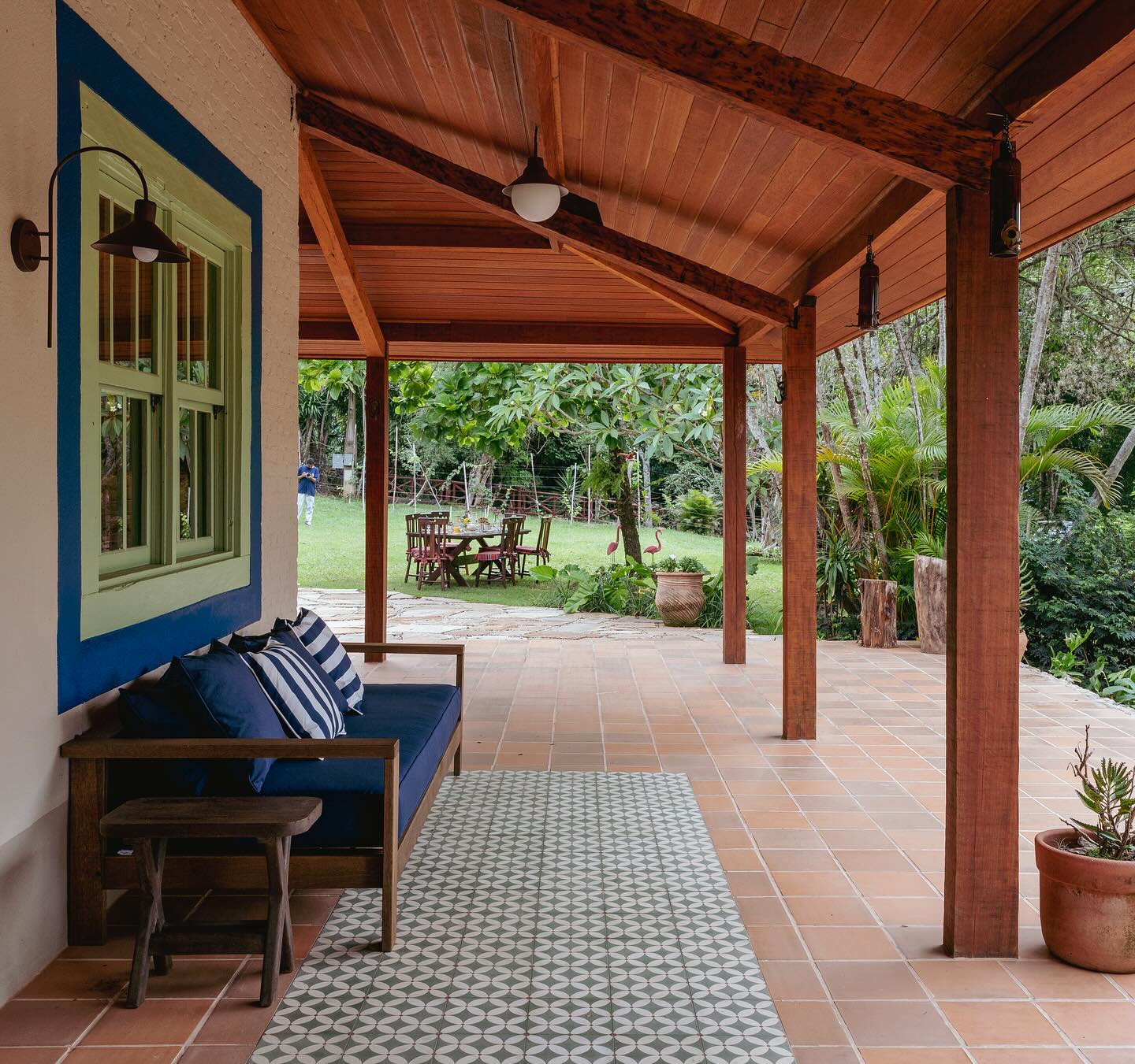 Área externa de casa centenária reformada com varanda coberta, espaço para encontros e integração com o paisagismo