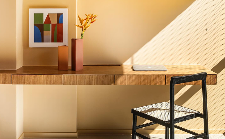 Ambiente com mesa de trabalho iluminada por luz natural, destacando a importância da iluminação no conforto visual do dia a dia.