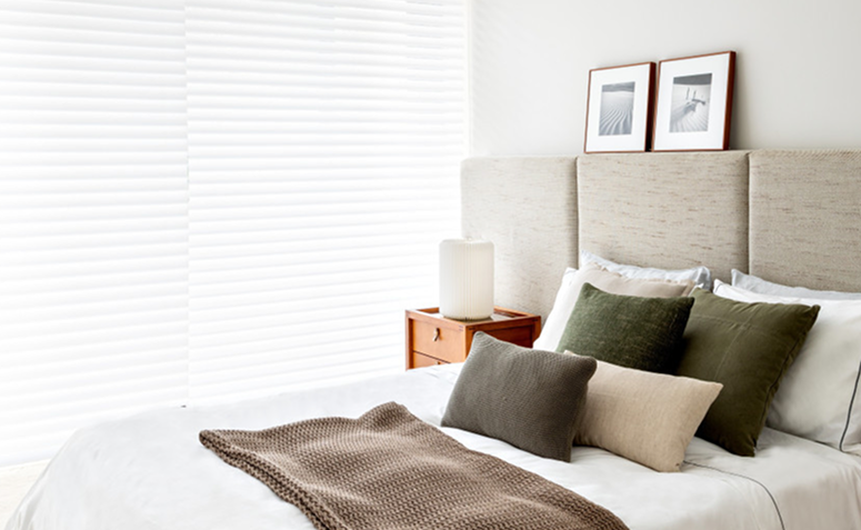 Quarto com decoração neutra, iluminação suave e poucos elementos, criando um ambiente silencioso e confortável para o descanso.