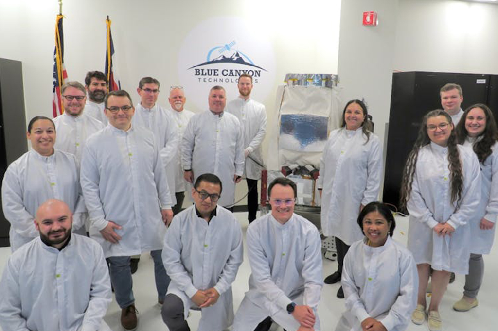 Fotografia dos integrantes da equipe Pandora SmallSat com o satélite concluído na sala limpa da Blue Canyon Technologies em Boulder, Colorado, antes de o Pandora ser enviado para a Califórnia para integração ao foguete Falcon 9 da SpaceX.
