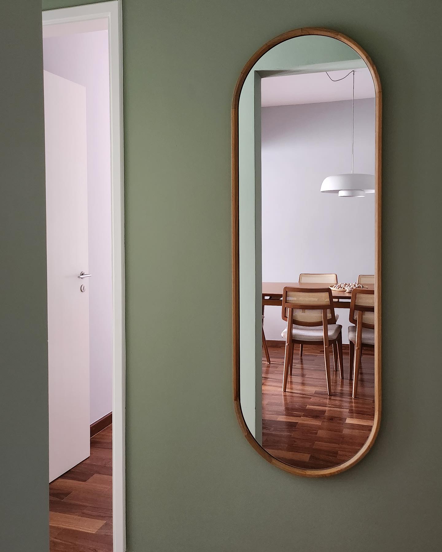 Espelho com moldura discreta em corredor de circulação.