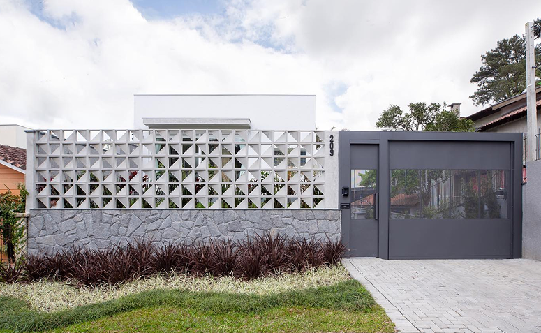 Muros e portão de acesso reforçado em residência, combinando proteção, visibilidade e design contemporâneo.