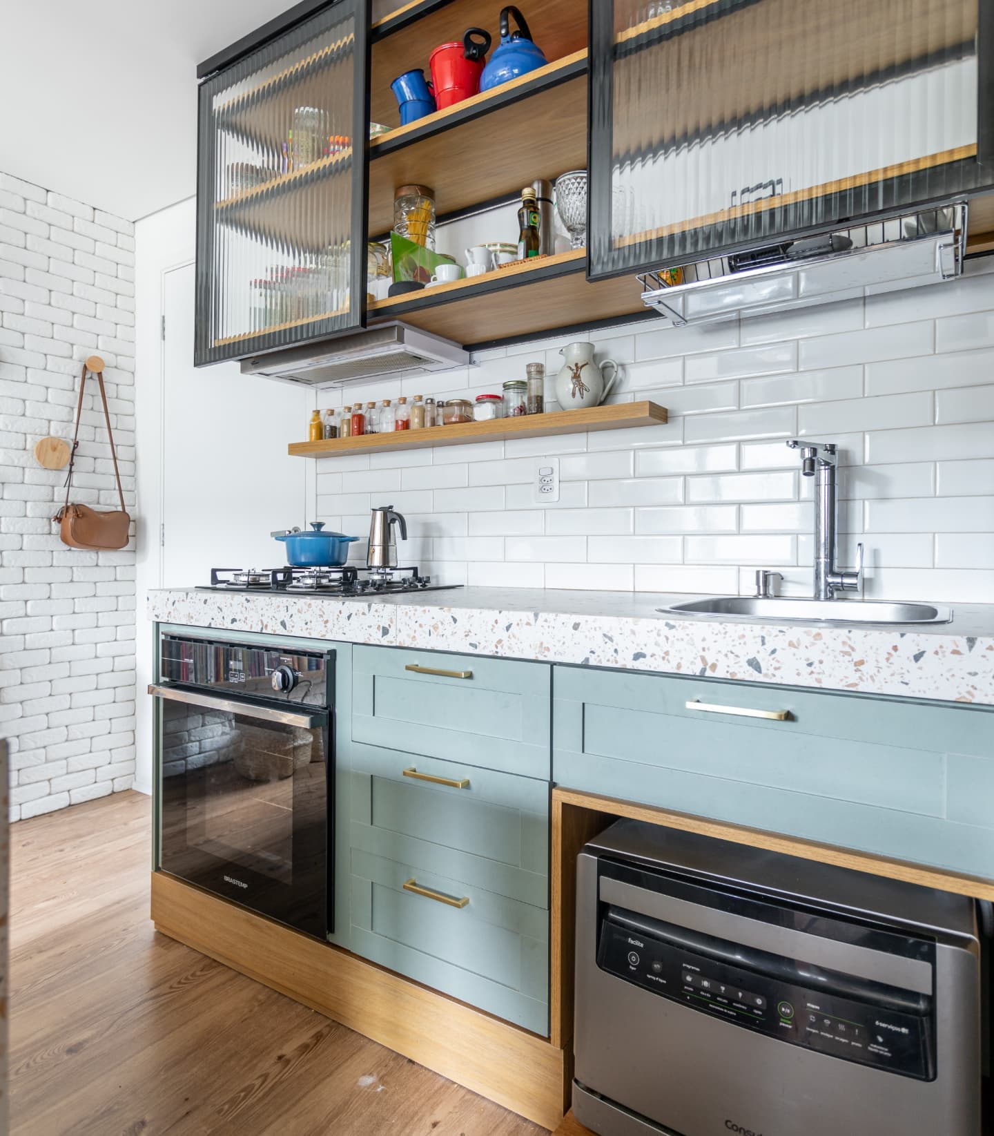 Cozinha compacta com marcenaria verde, bancada multifuncional e armários em vidro canelado