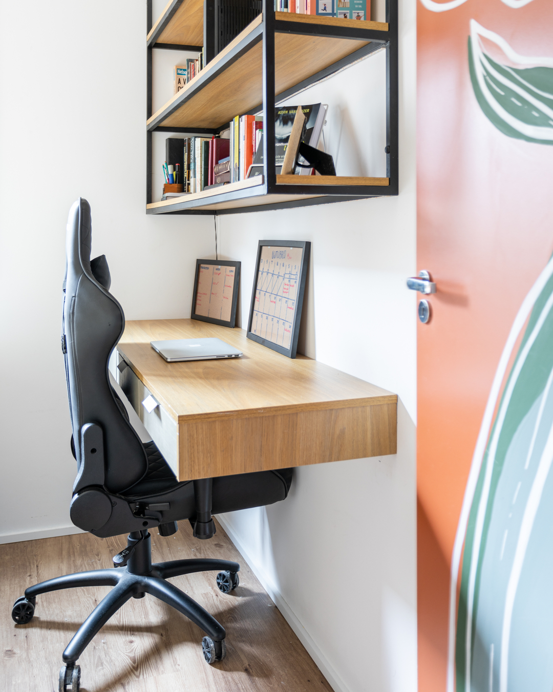 Home office compacto integrado ao quarto em apartamento pequeno, com bancada suspensa e estante