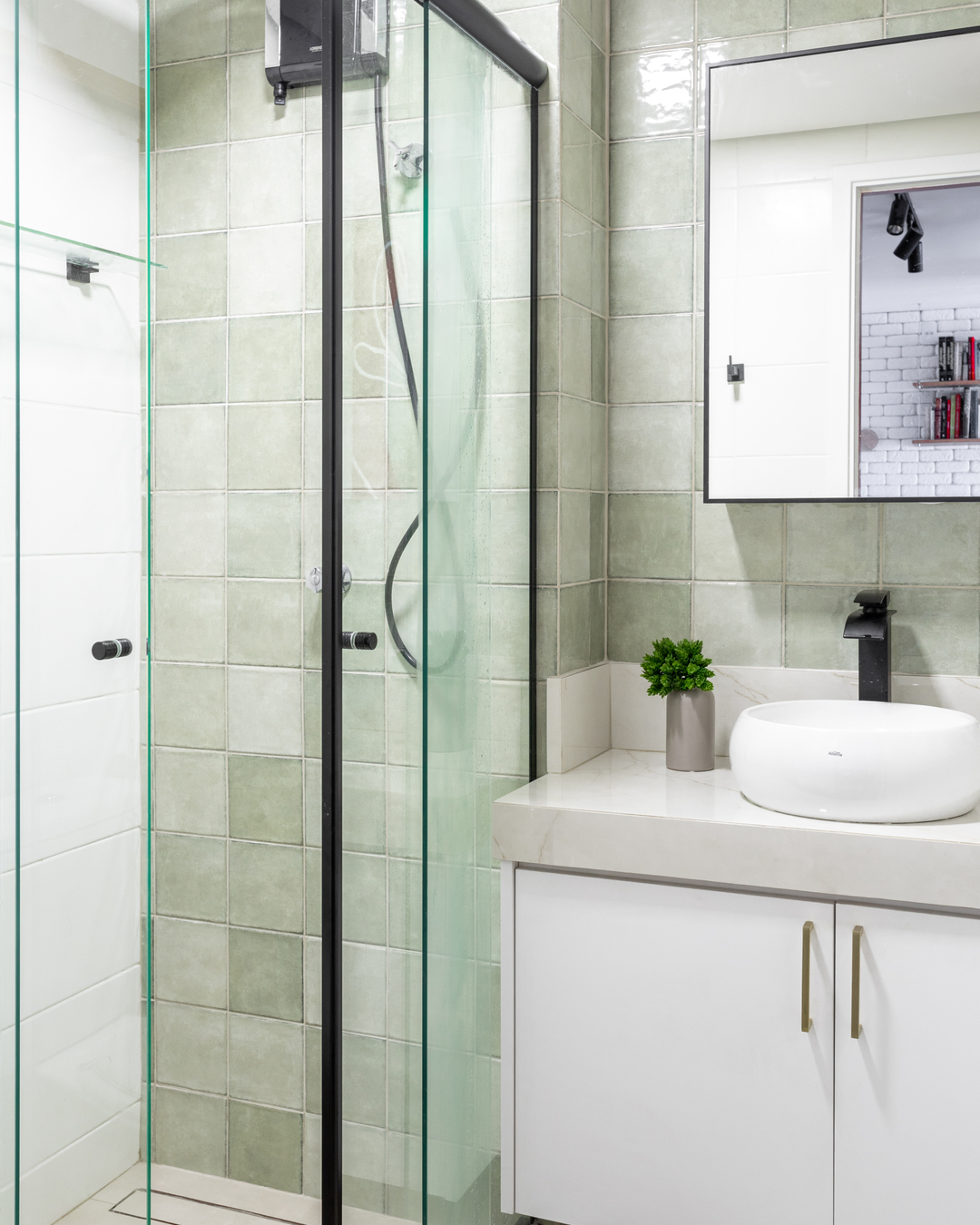 Banheiro funcional em apartamento de 25 m² com marcenaria sob bancada e box de vidro transparente