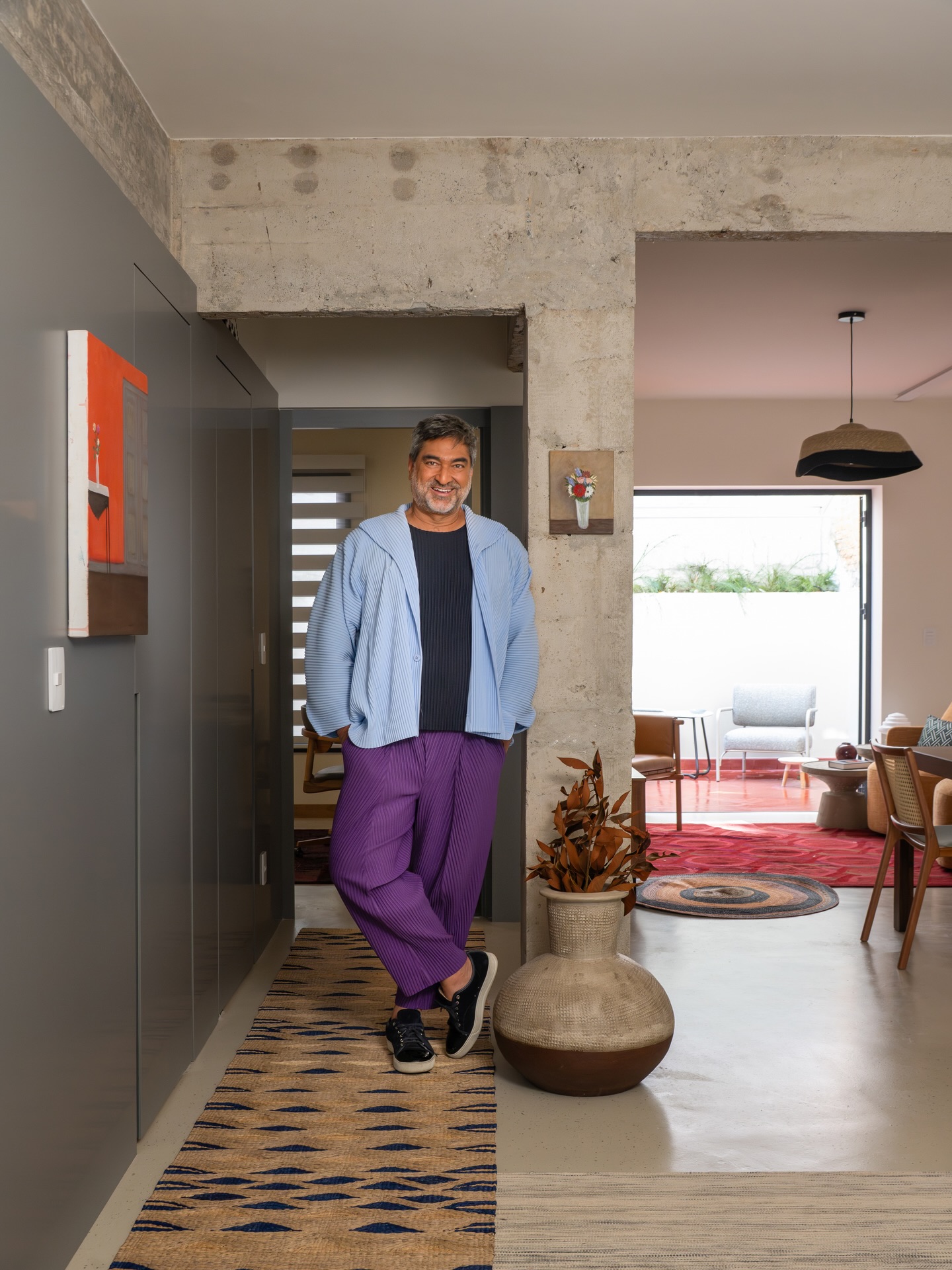 Zeca Camargo apoiado em um pilar de concreto na área social de seu apartamento.