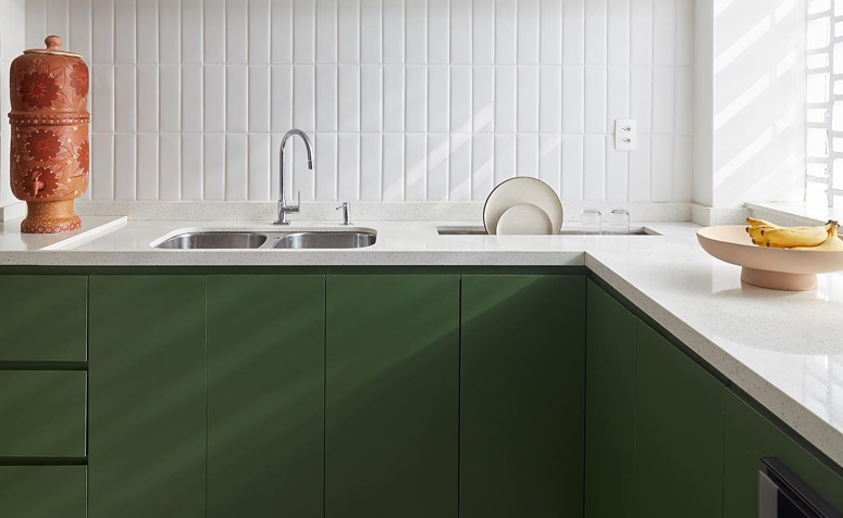 cozinha com armários verde-musgo e decoração leve com branco.