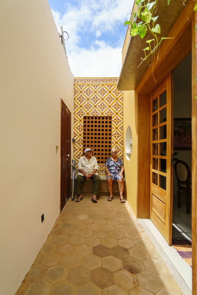 Pais de Zé, arquiteto da casa, sentados em um banco na área externa da casa.