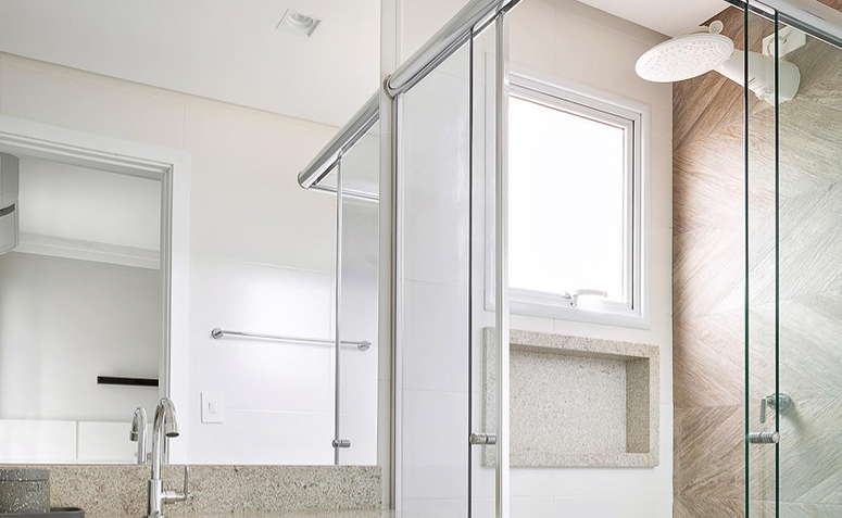 Banheiro decorado com chuveiro elétrico, representando dicas para economizar água e luz no banho