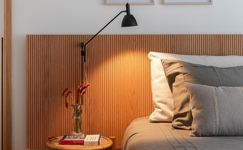 luminária de parede iluminando cabeceira de cama em quarto, exemplo de iluminação no ambiente de descanso