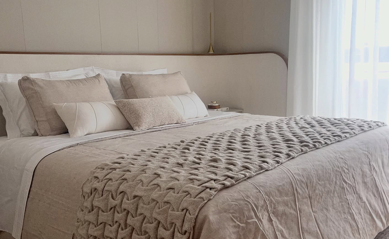 cama com colchão confortável e travesseiros bem apoiados em quarto com decoração neutra