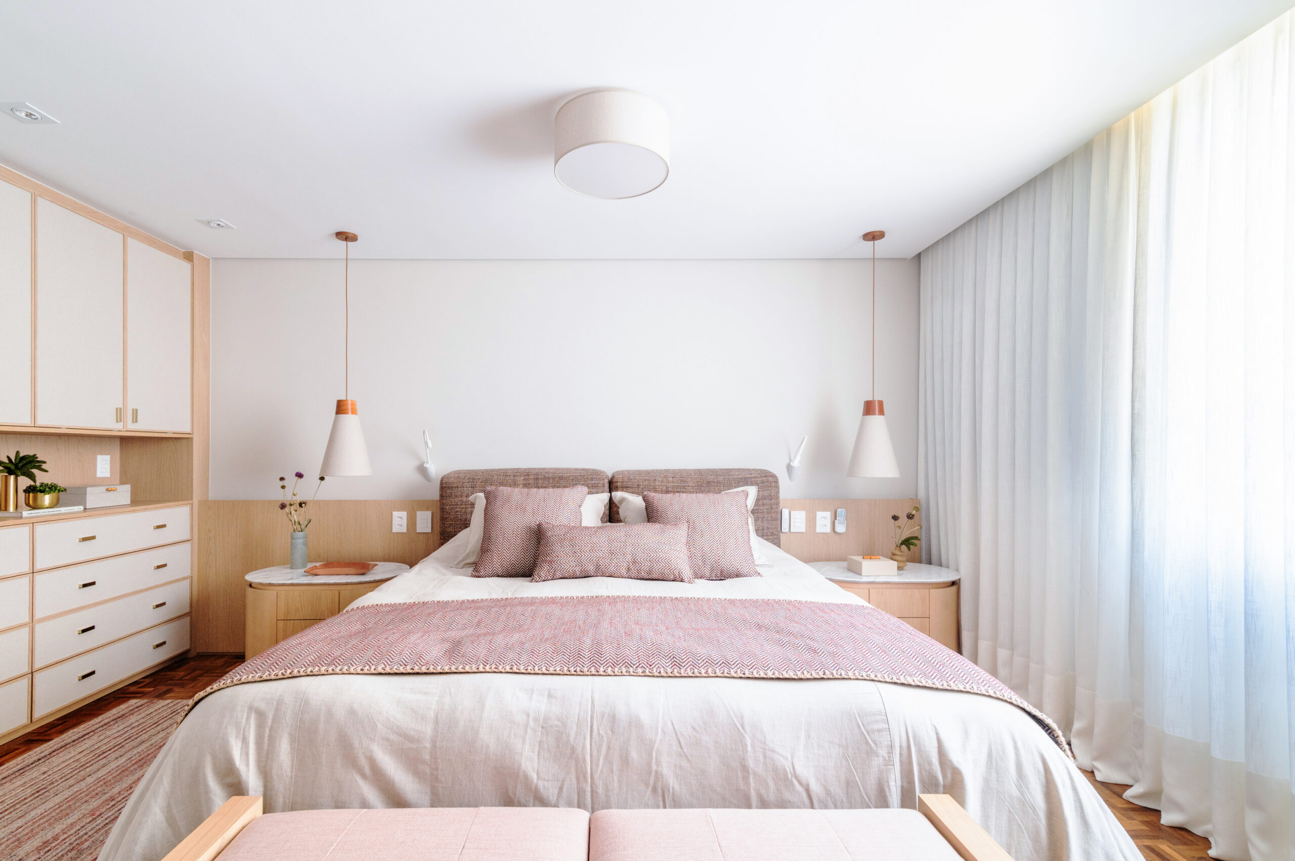 Vista ampla da suíte master, mostrando cama de casal, roupeiro e janelas.