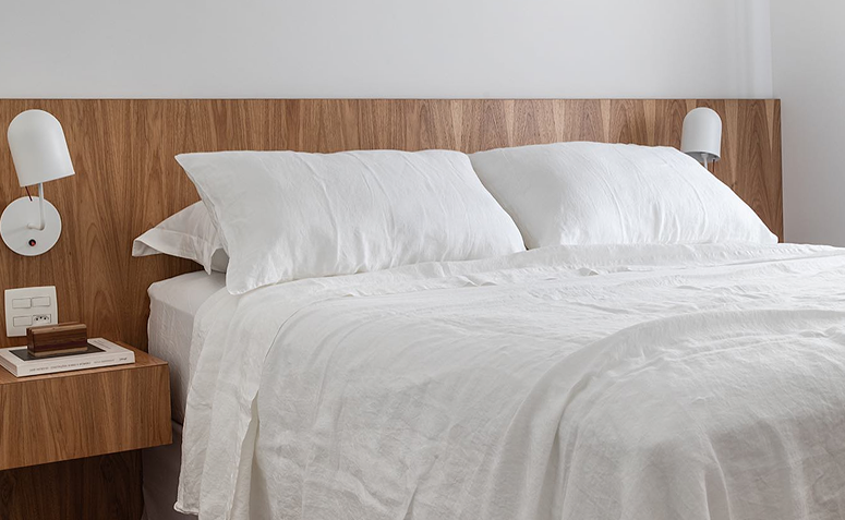 cama com roupa de cama branca e colchão em destaque em quarto minimalista