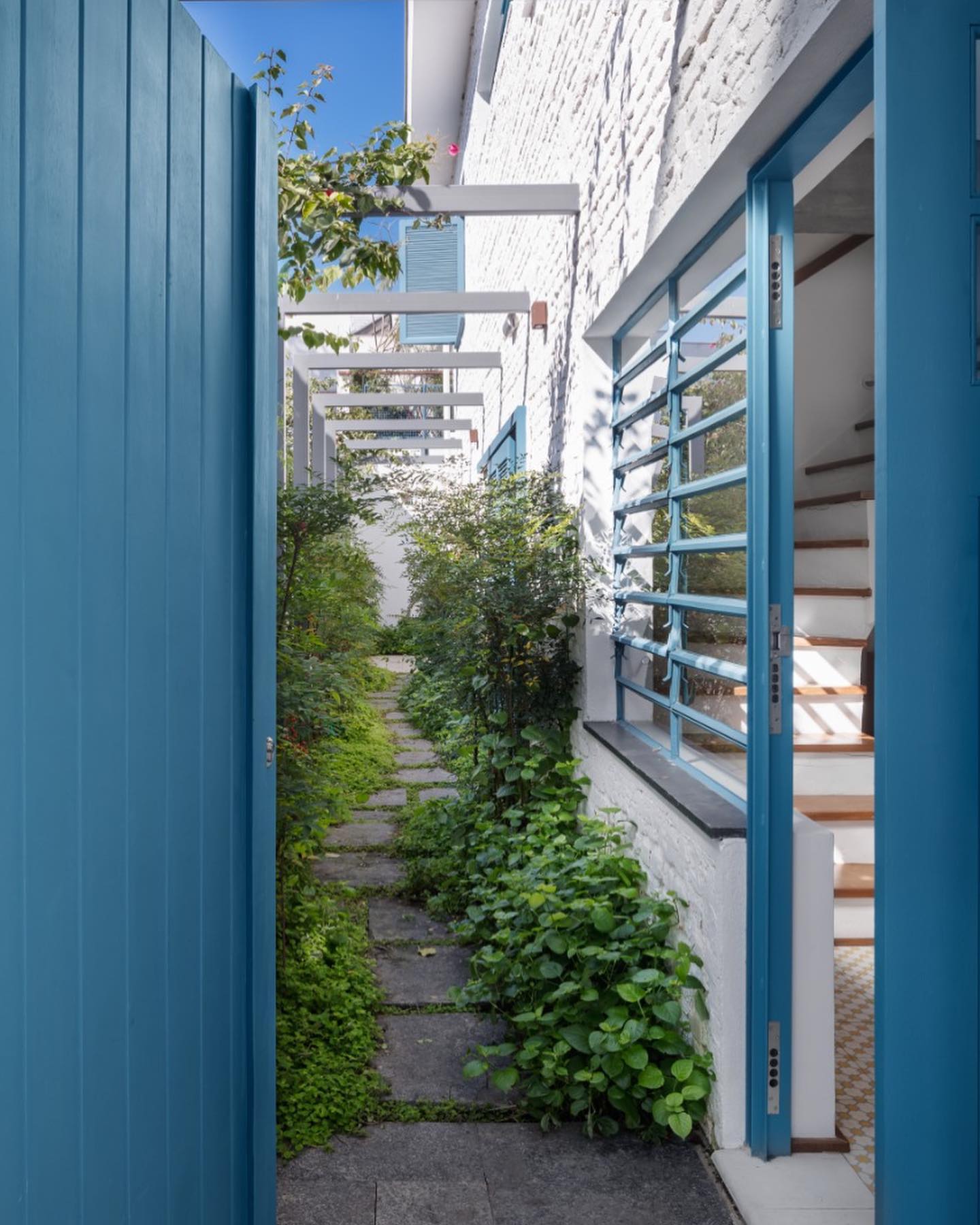 Corredor externo com canteiro lateral e paisagismo simples com plantas verdes ao longo do caminho.
