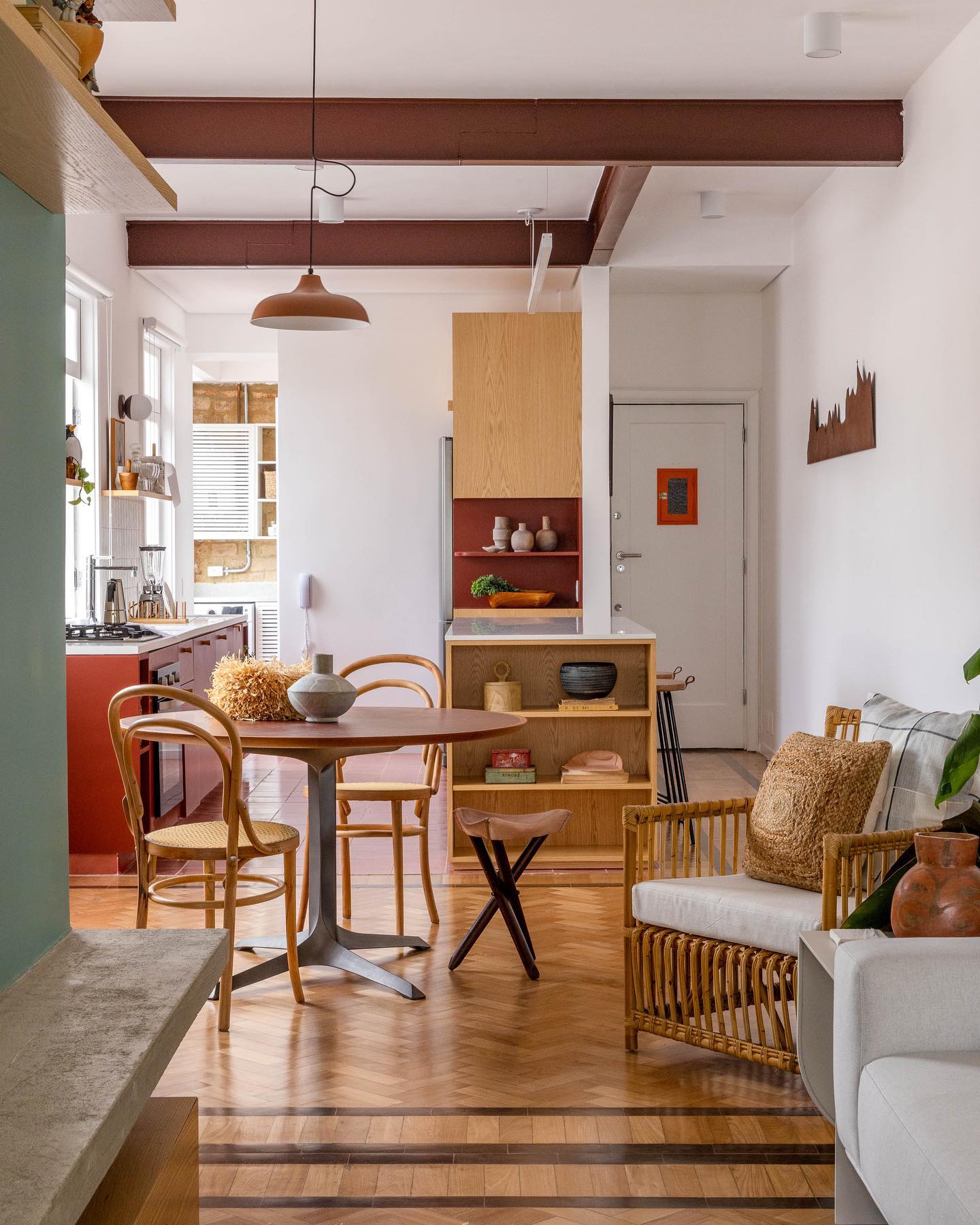 Sala integrada com mesa de madeira, cadeira de fibras naturais e piso em parquet na decoração