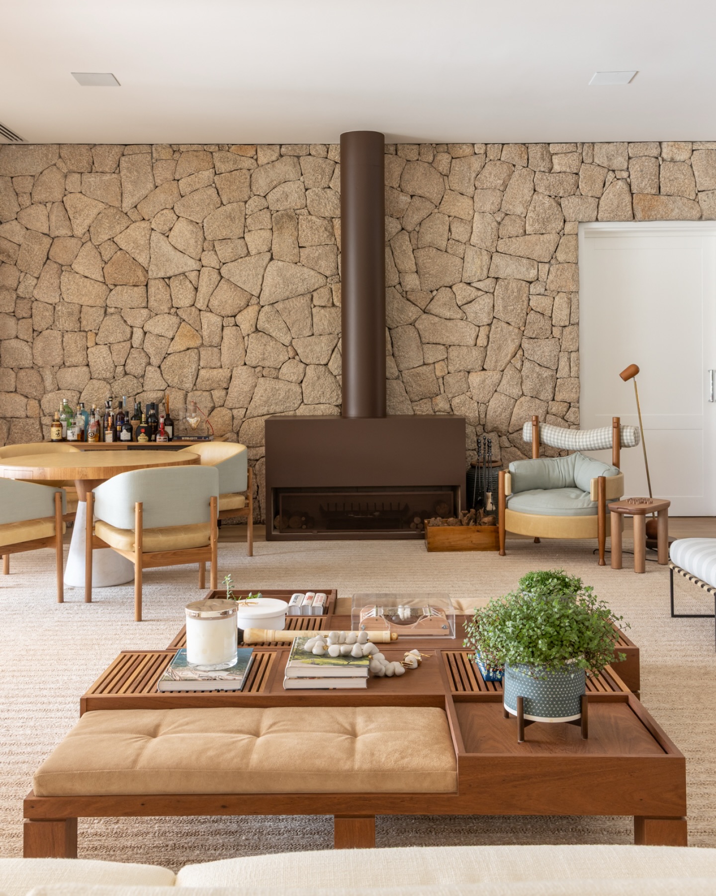 Sala com parede de pedra natural, móveis de madeira e tapete de fibras naturais na decoração