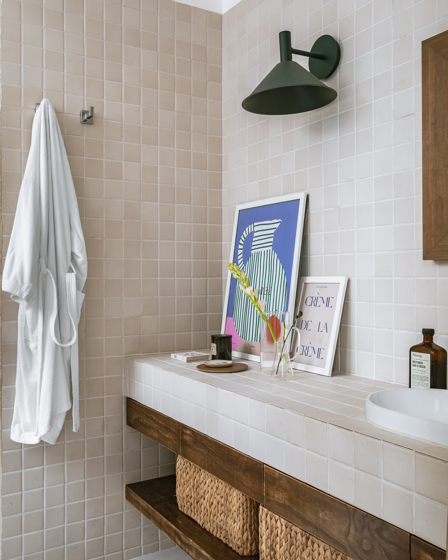 Banheiro com bancada de azulejos claros, móvel de madeira e cestos de fibras naturais na decoração