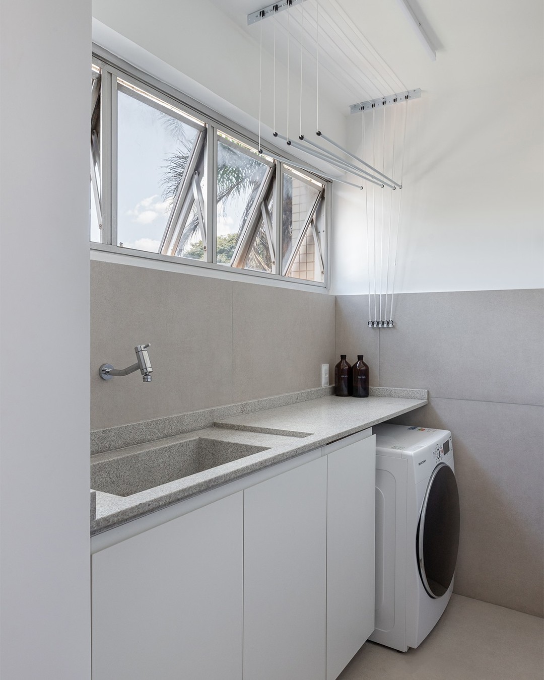 lavanderia branca com varal de teto e iluminação natural