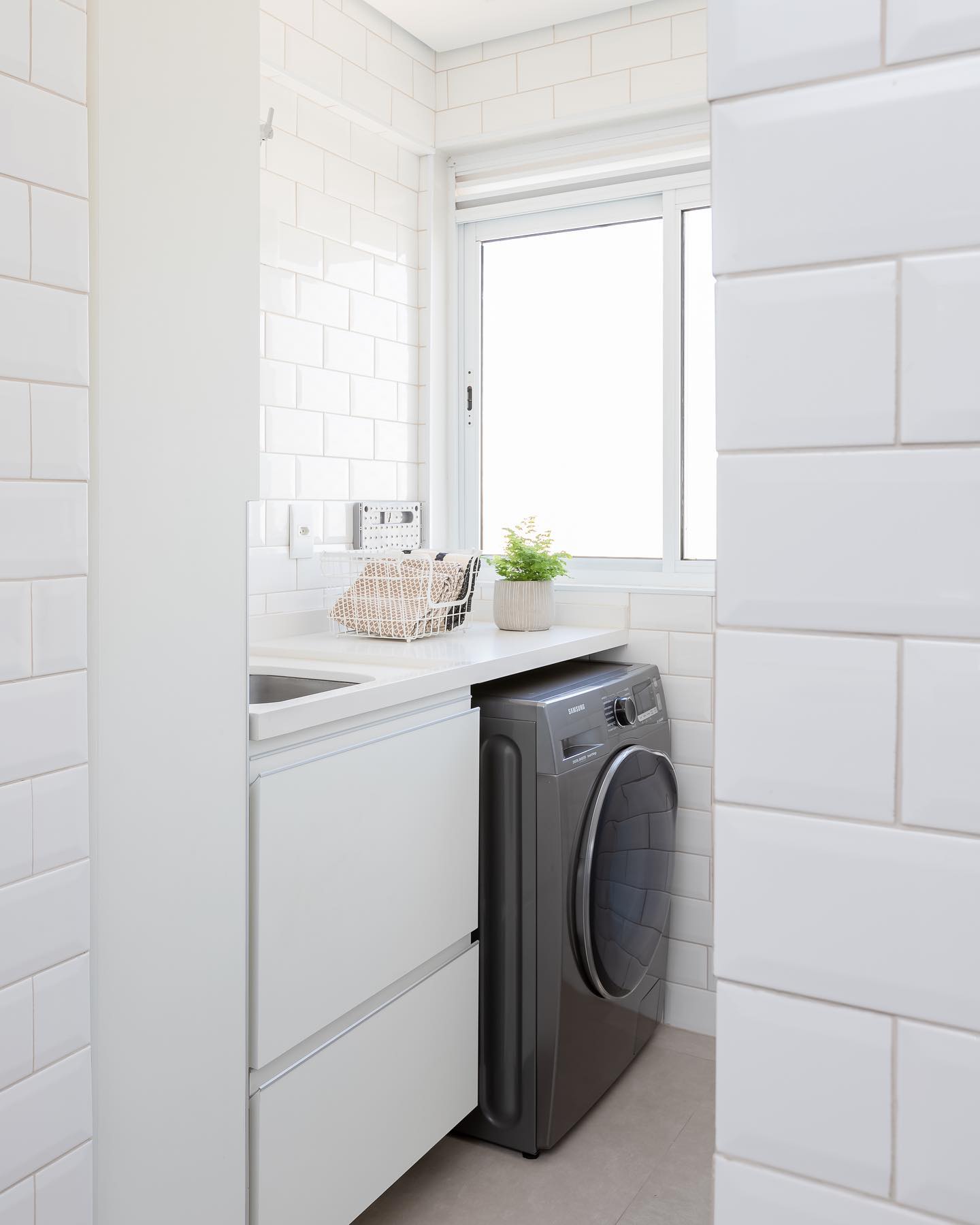 lavanderia branca pequena com bancada e máquina embutida