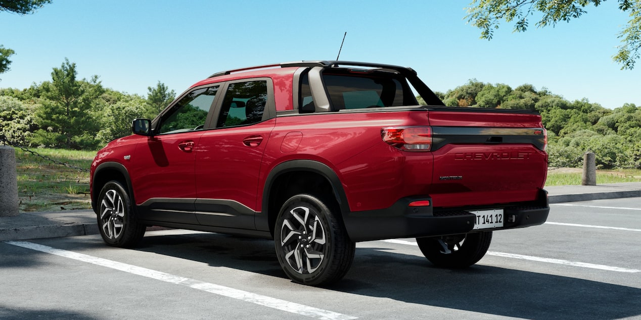 Vista traseira da Chevrolet Montana na cor Vermelho Scarlet estacionada em ambiente arborizado e ensolarado