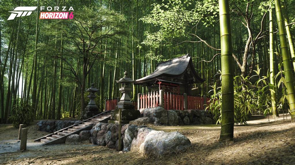 Templo japonês tradicional com telhado escuro e cerca vermelha, cercado por um denso bambuzal verde. Escadas de pedra levam ao templo, ladeadas por lanternas de pedra e rochas. O chão é de terra batida com folhas secas, e o sol ilumina a cena. O logotipo