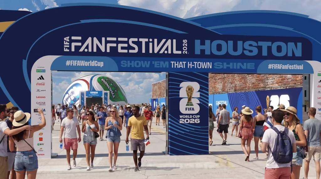 Pessoas caminhando em um festival ao ar livre da FIFA em Houston, com um grande portal azul escrito