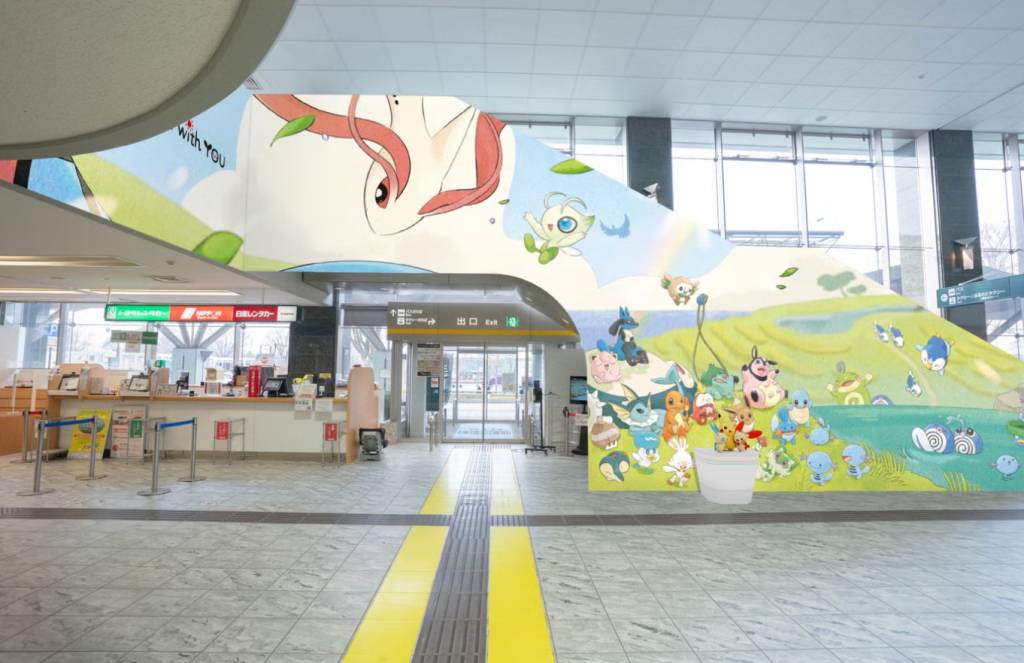 Interior de um saguão com balcão de atendimento e um mural colorido de Pokémon. O mural mostra Latias e Celebi no alto, e vários Pokémon como Pikachu, Lucario e Vaporeon em uma paisagem verde com um lago. No chão, há faixas táteis amarelas e cinzas, e um balde branco com pequenos bonecos Pokémon. Ao fundo, portas de vidro e janelas revelam o exterior