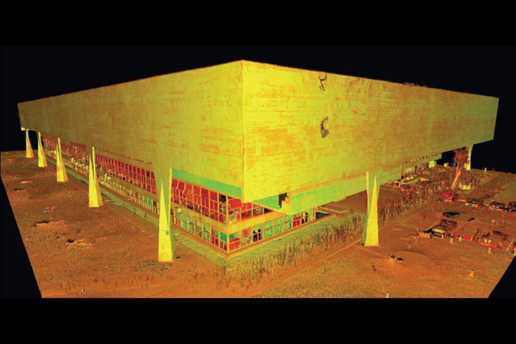 Modelo 3D de um edifício retangular com fachada amarela e janelas vermelhas e azuis, sustentado por pilares triangulares em um terreno marrom-alaranjado, sobre fundo preto