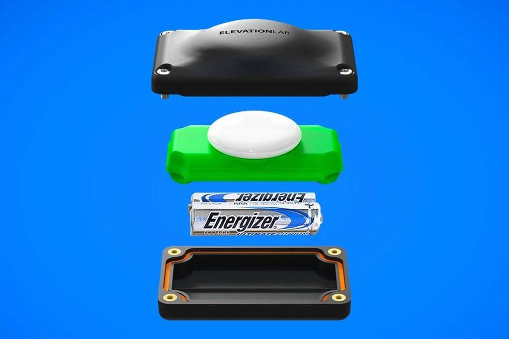Componentes de um dispositivo ElevationLab: uma tampa preta com o nome da marca, um AirTag branco sobre uma base verde, duas pilhas Energizer Ultimate Lithium e a base inferior preta com borda laranja.