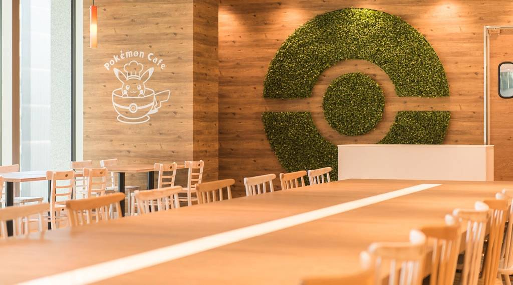 Interior de um café com paredes de madeira clara. À esquerda, um logo branco do